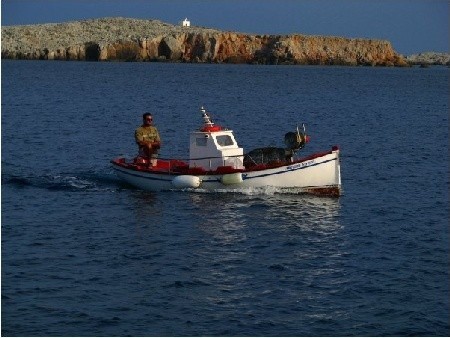 Rybak wracający do portu Karavostassi... w tle: skała (wysepka)  Agios Ioannis  