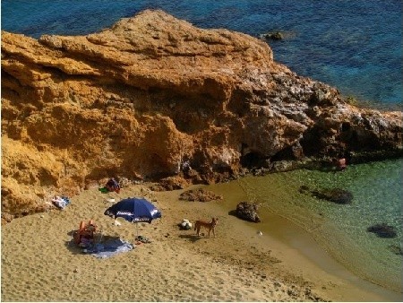 Po prawej stronie kościółka piaszczysta plaża  Aghii Anarghiri z takim przepięknym zielonym kolorem wody, kilkoma wypoczywającymi  osobami i biegającym psem